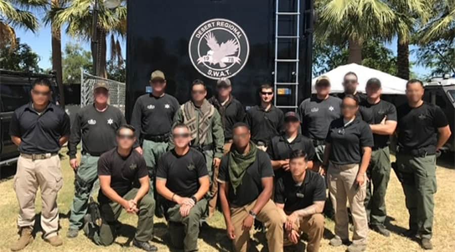 a group of men and women posing in front of a SWAT vehicle