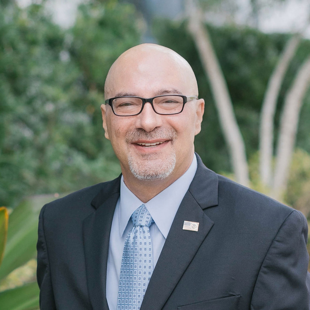 SummitET-Adam-Montella-2024 Man in business suit wearing glasses and smiling