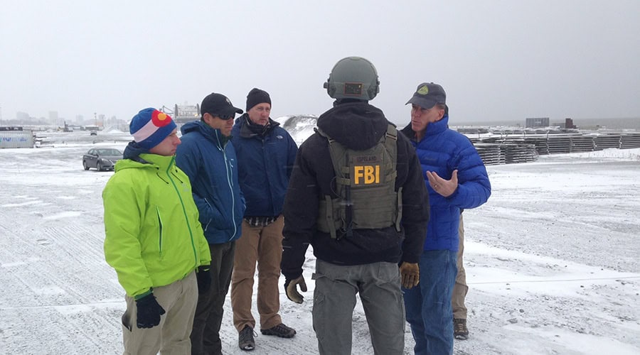 A group of people in winter coats being given instructions by one man